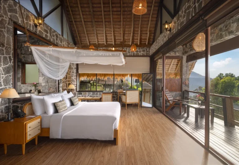 Stone-walled bedroom with a canopy bed and mountain-view balcony at 98 Acres Resort and Spa