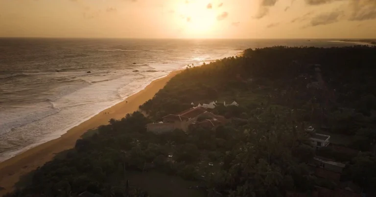 Sun setting over the ocean and coastline beside Aditya Resort