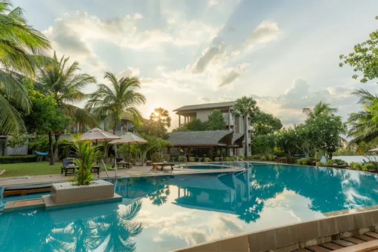 Swimming pool bordered by palms and tropical gardens at Amaranthe Bay Resorts and Spa