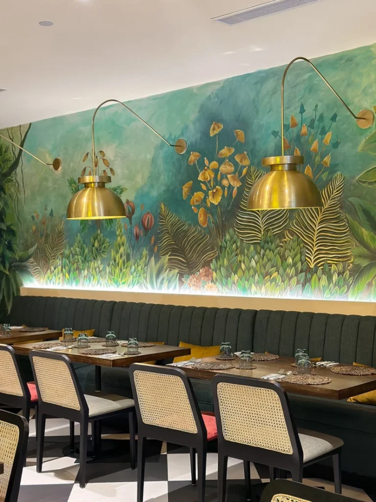 Banquette seating, dining tables and a green botanical mural at Amma Nissa, One Galle Face, Colombo.
