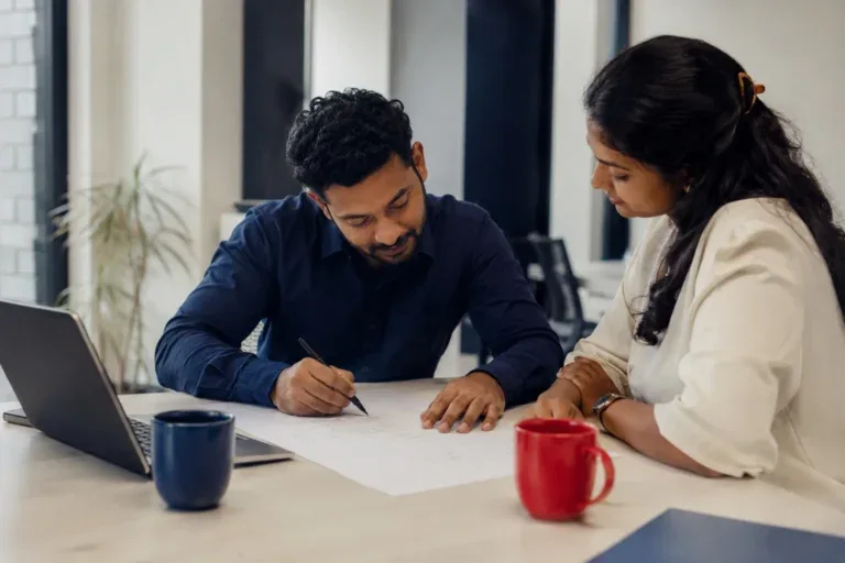 Two people reviewing project plans at a desk, featured on Ants Creation’s website