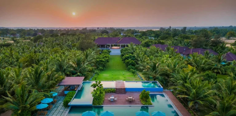 Aerial view of Aprota Villas with swimming pools and palm trees at sunset