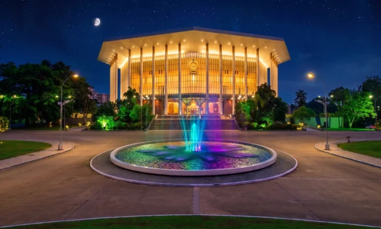 BMICH illuminated at night with a colourful fountain in front of the main hall