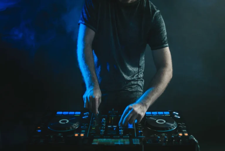DJ operating mixing decks under blue stage lighting