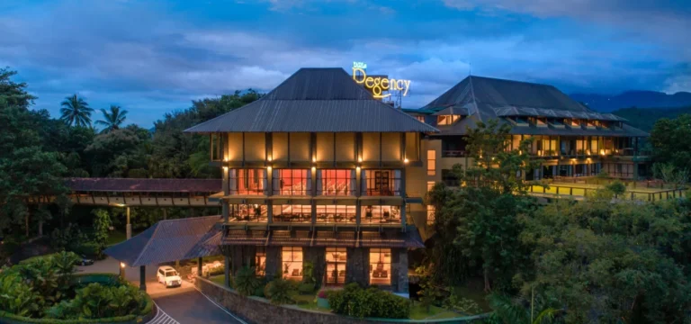 Earl’s Regency Hotel illuminated at dusk among green hills