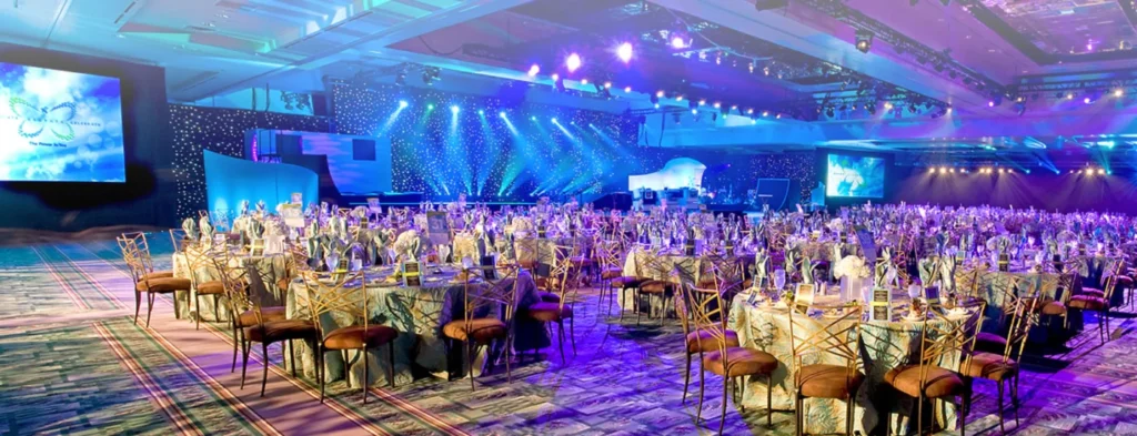 Banquet venue with round tables and blue stage lighting