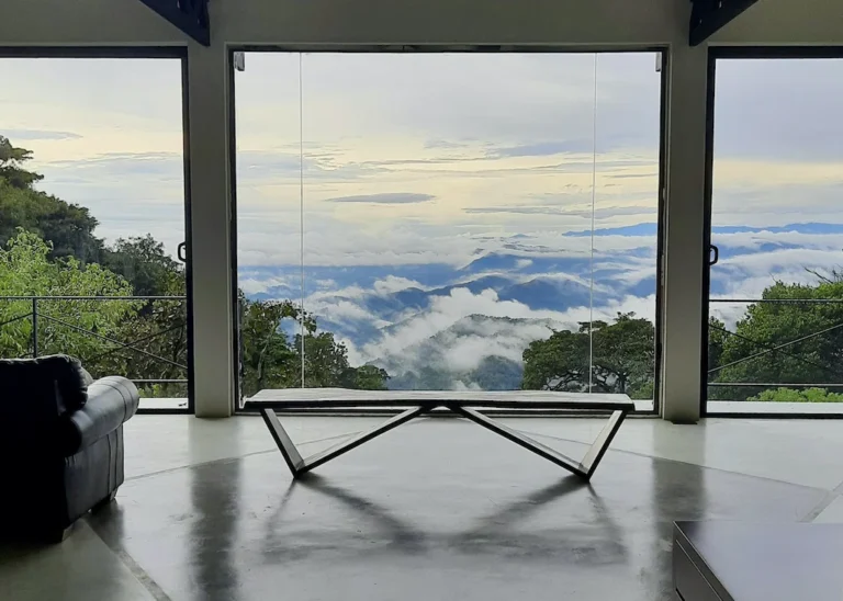 View through large windows over green hills and low clouds at GlenMyu Estate