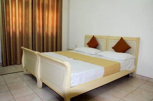 Guest bedroom with a double bed and gold curtains at Gondolas Holiday Lanka