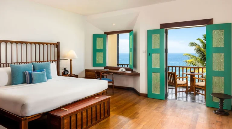 Bedroom with turquoise shutters and an ocean-facing balcony at Jetwing Lighthouse in Galle.