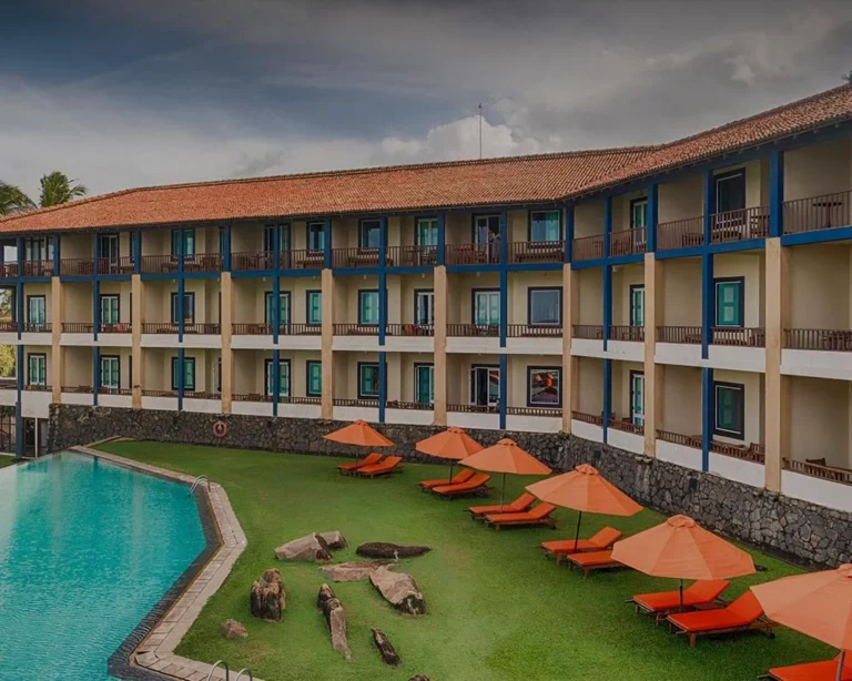 Jetwing Lighthouse guest-room balconies above the swimming pool and orange parasols