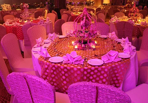 Wedding reception tables decorated with flowers under pink lighting