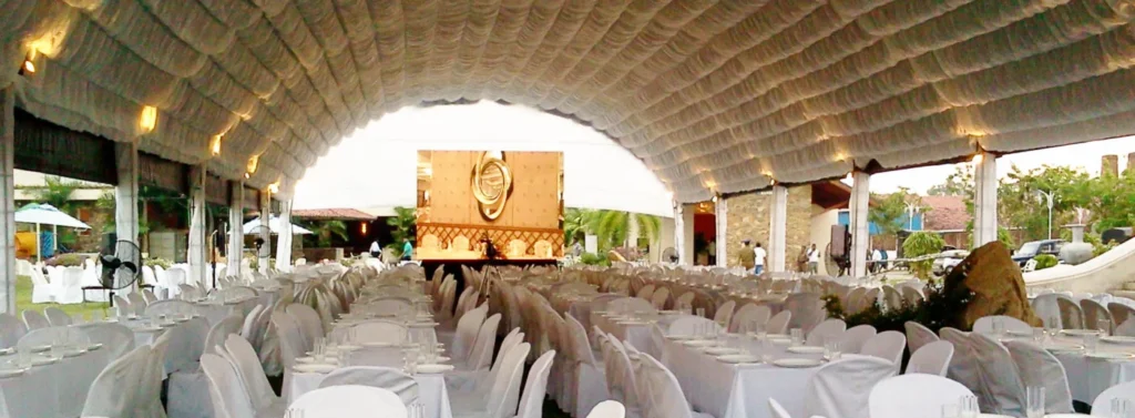 Covered event venue arranged with white chairs and banquet tables