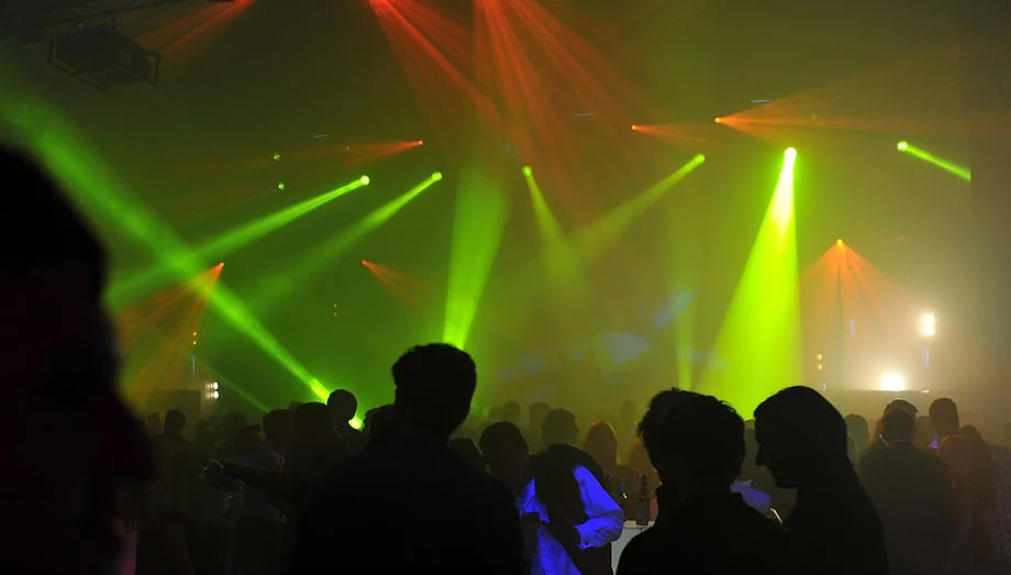Green stage lights above an audience at an indoor event